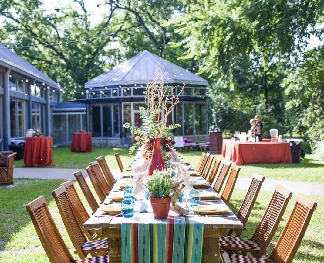 A long banquet table set for an event on the lawn at the UMLAUF Sculpture Garden