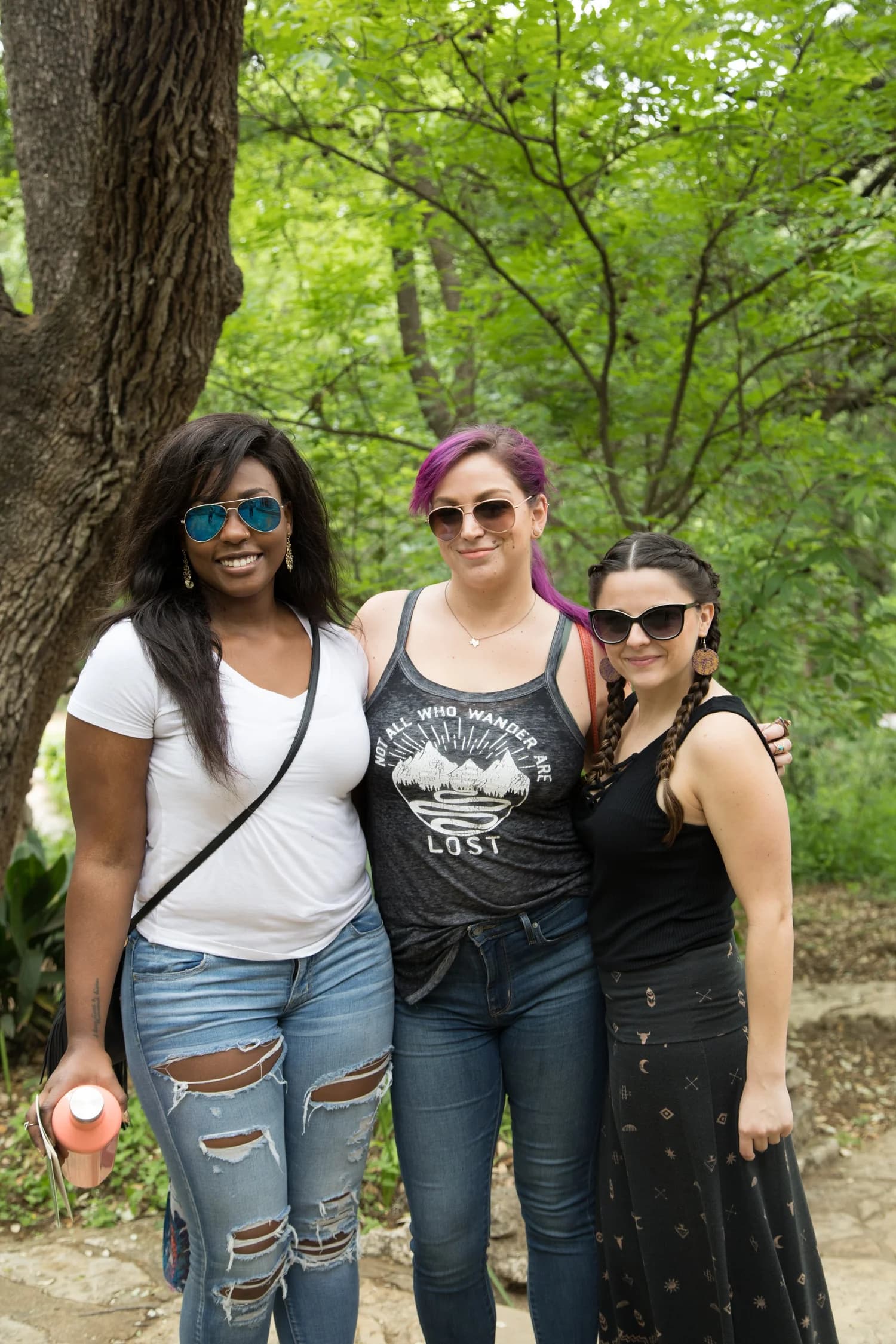 Three friends posing together along a shaded greenbelt trail
