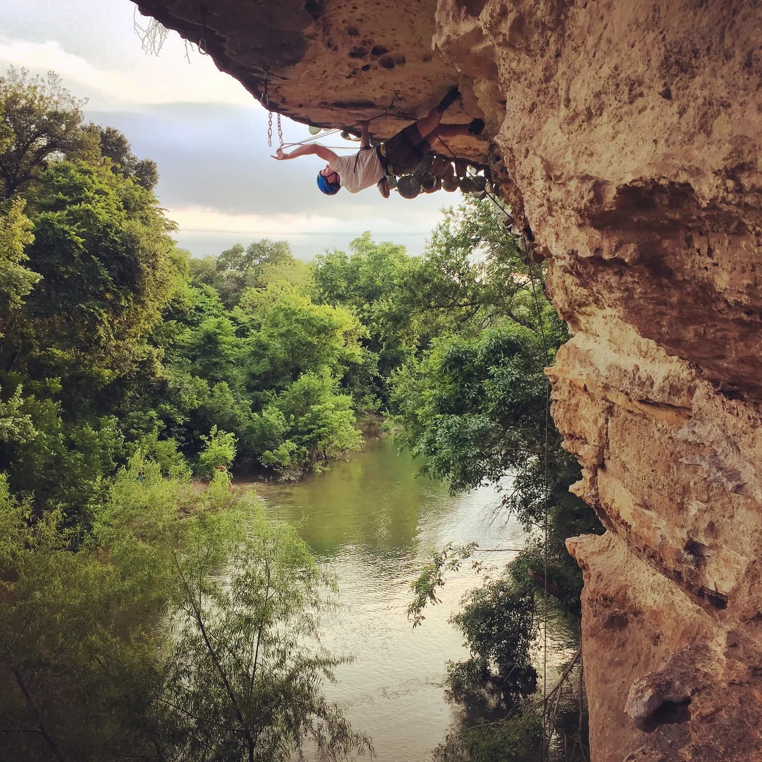 A climber on the overhanging limestone climbing wall above Barton Creek