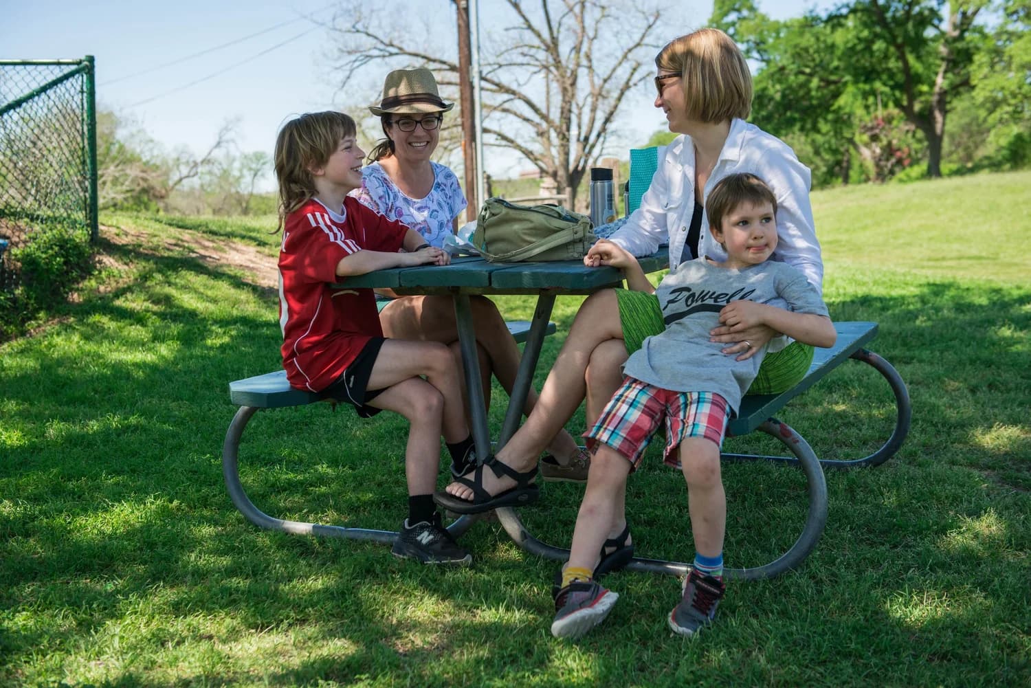 A family gathered around a picnic table in the park on a sunny day