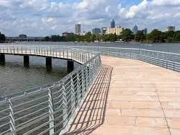 The boardwalk section of the Butler Hike-and-Bike Trail curving along Lady Bird Lake with the Austin skyline beyond