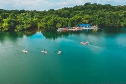Paddleboarders and kayakers on Lady Bird Lake near the colorful Rowing Dock
