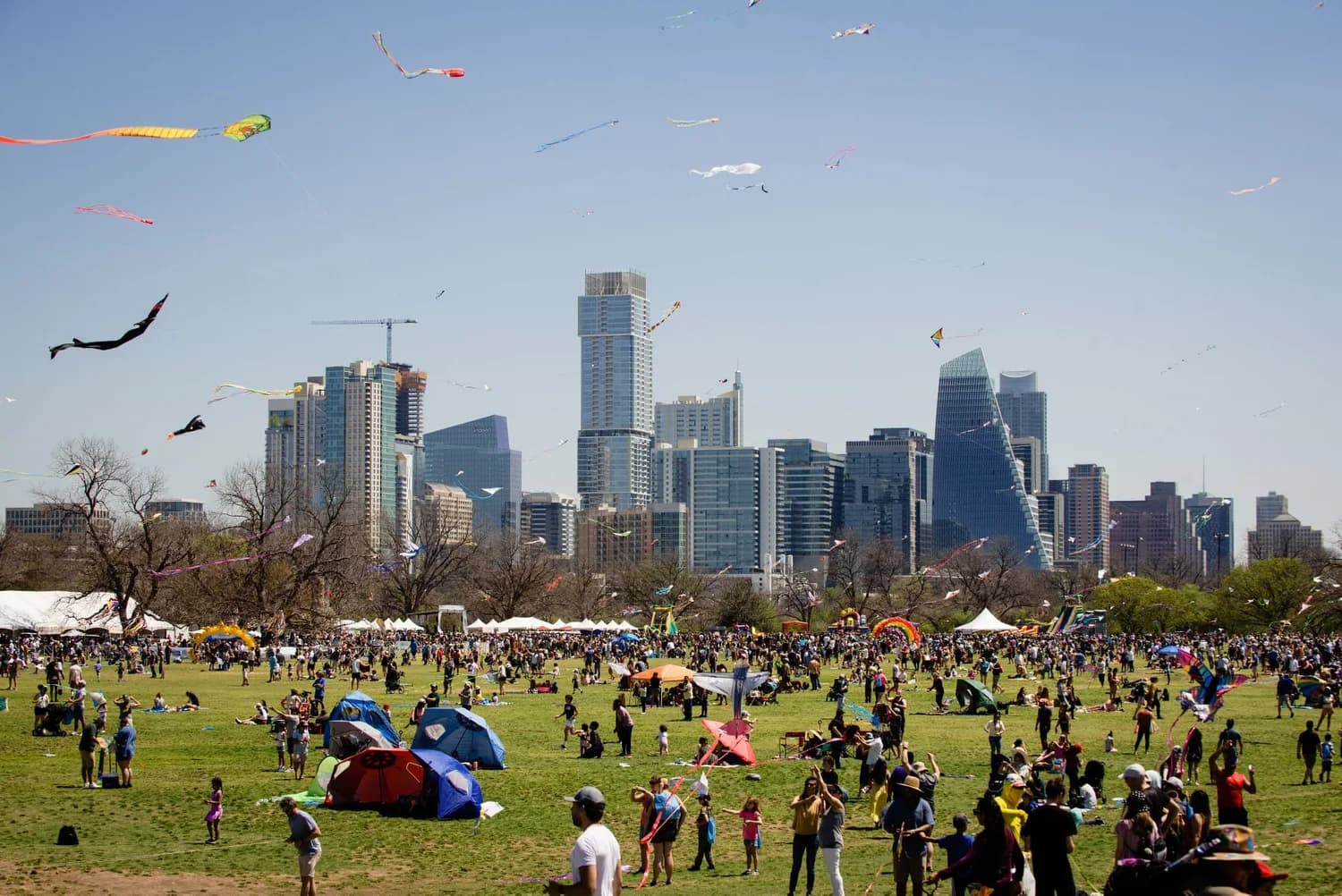 Kite Fest crowds on the Zilker great lawn with the Austin skyline behind